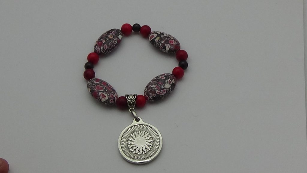 PULSERA DE CUARZO ROJO CON DIJE DEL ENEGRAMA SOLAR DE PLATA